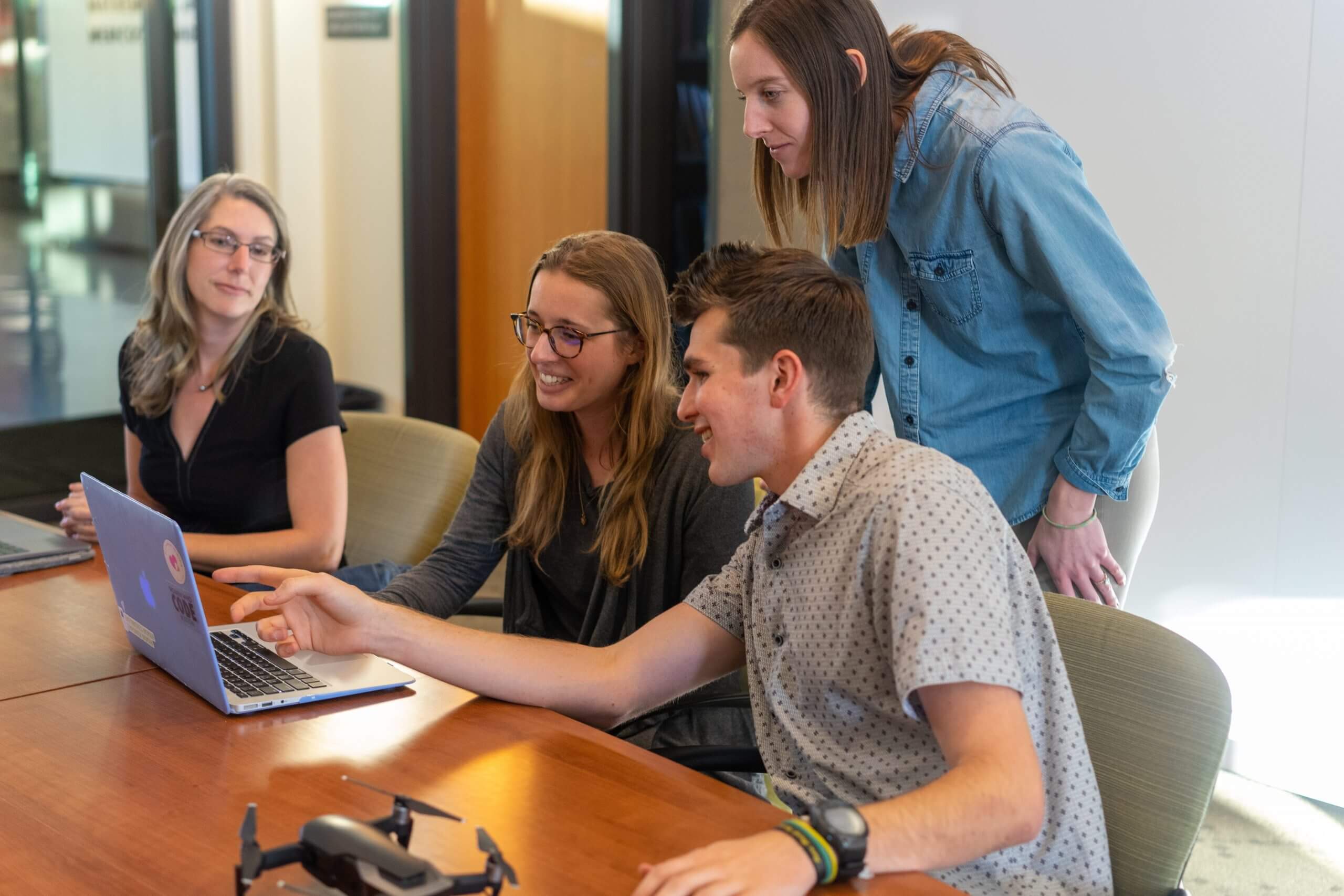 Group of employees sitting at a table looking at laptop screen